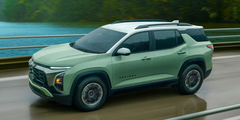 Green Chevrolet Equinox driving on a bridge near water.