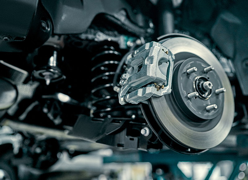 A close-up shot of a car's disc brake assembly and suspension system.