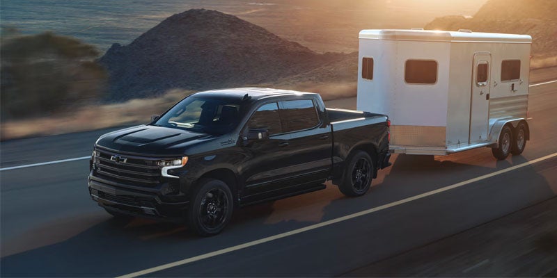 2026 Chevrolet Silverado 1500 hauling a horse trailer on the open highway.